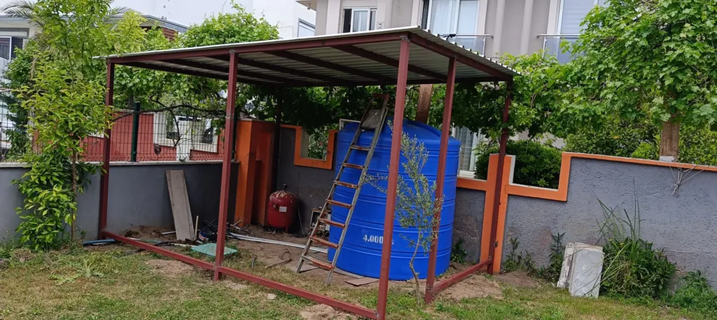 Bahçede çelik profilli sundurma iskeleti ve sac örtü montajı