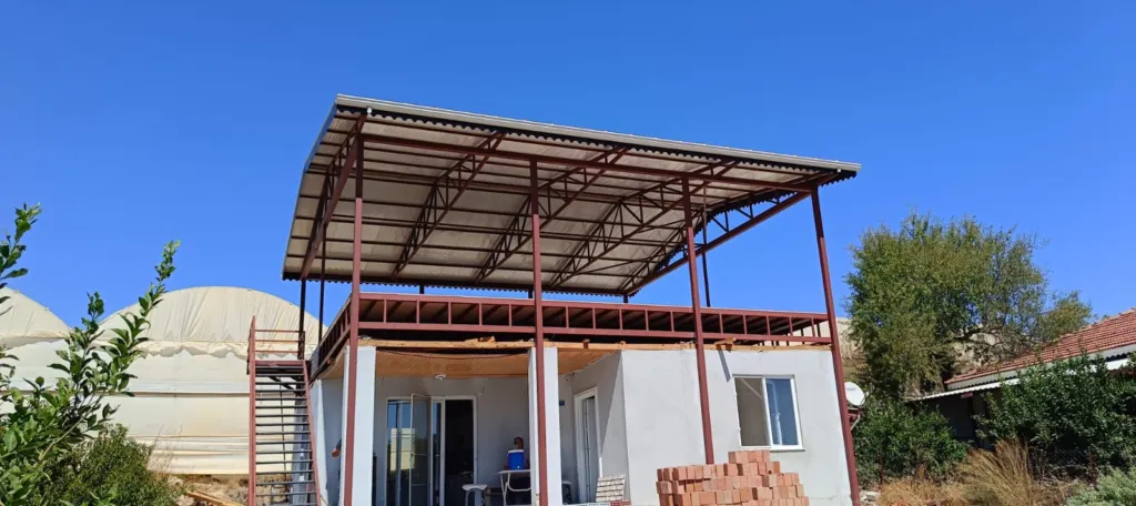 Yapı terasında kırmızı çelik taşıyıcı üzerine sac gölgelik montajı