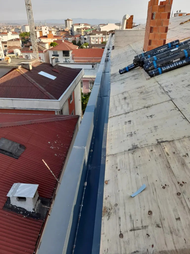İki bina arasında gri gizli dere sacı ve membran ruloları