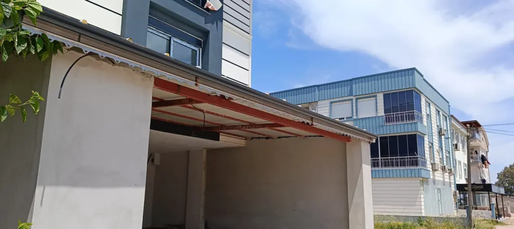 Saçak altında ahşap mertekler ve kenarda gri metal oluk