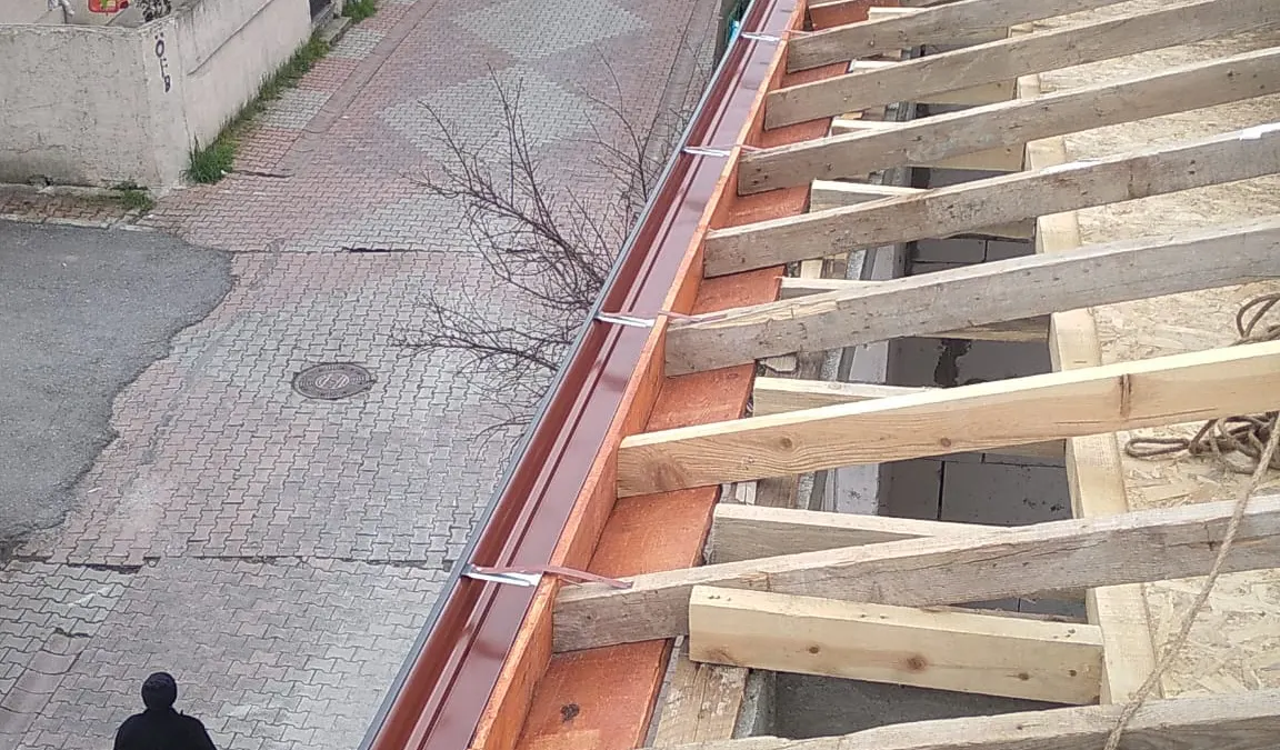 Ahşap çatı iskeleti kenarına monte edilmiş bordo dere sacı