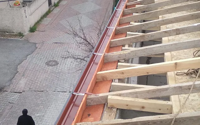 Ahşap çatı iskeleti kenarına monte edilmiş bordo dere sacı