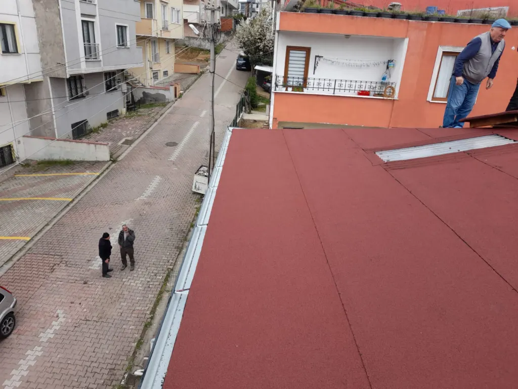 Bordo membran kaplı çatı kenarında oluk ve ayakta duran usta